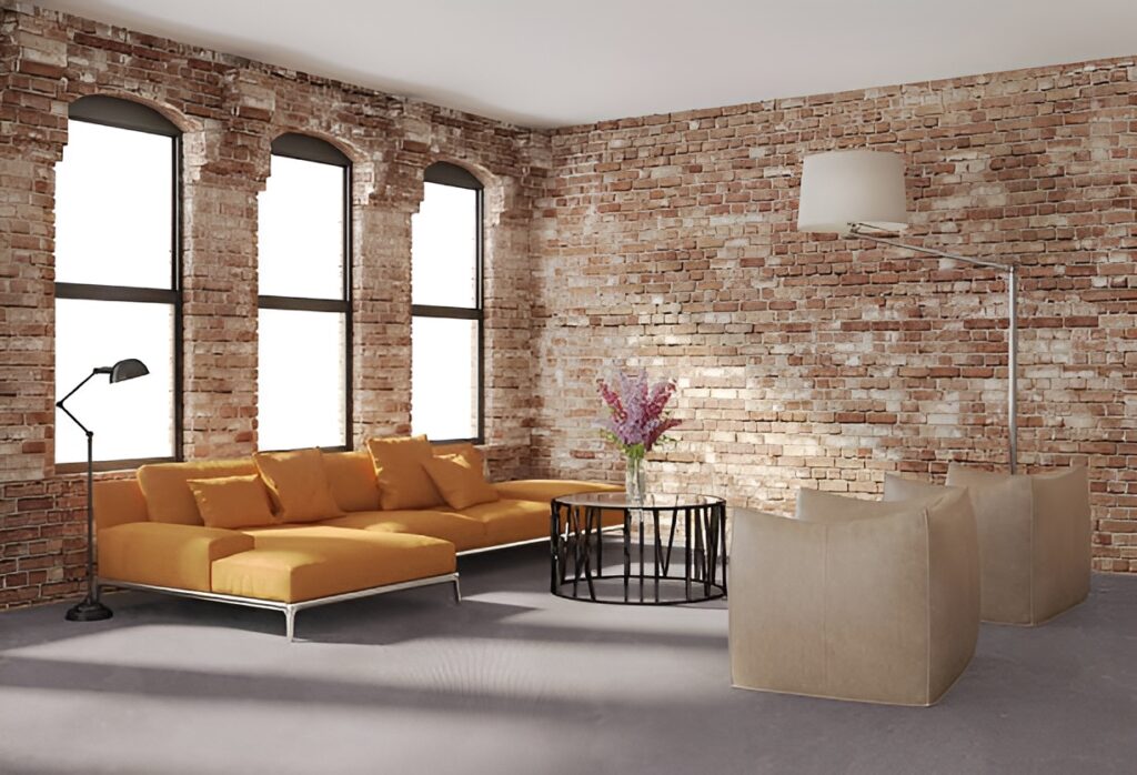 Services in Manhattan. Industrial-style living room with exposed brick walls, three tall arched windows, a mustard yellow sectional sofa, two beige armchairs, a black round coffee table, and modern floor lamps.