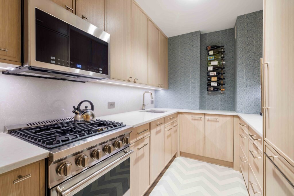 Contemporary kitchen with light wood cabinetry, stainless steel appliances, quartz countertops, and a wall-mounted wine rack
