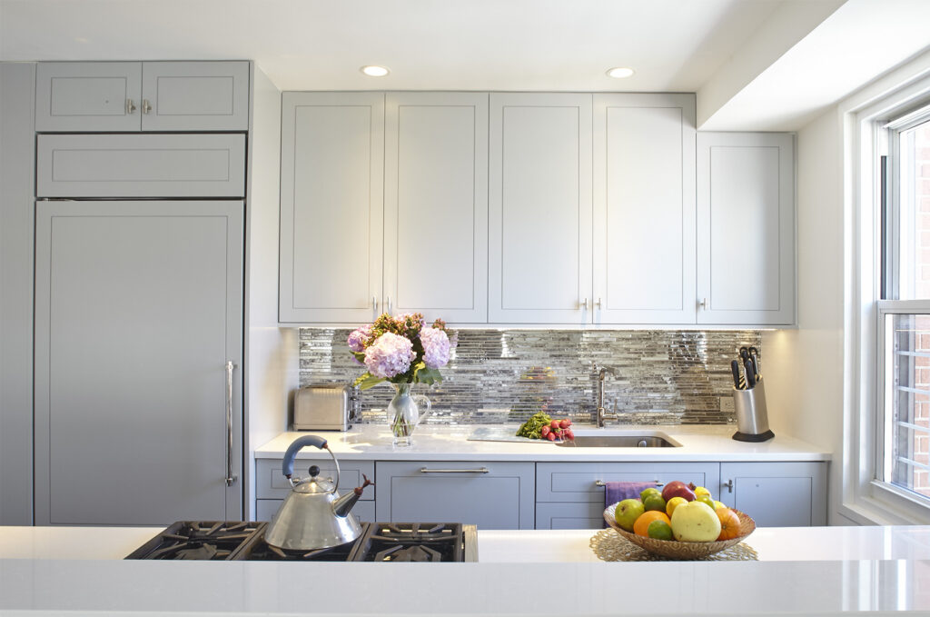 Polished urban kitchen featuring a textured stone backsplash, high-arc faucet, and strategically layered lighting for warmth and everyday function in city apartments.