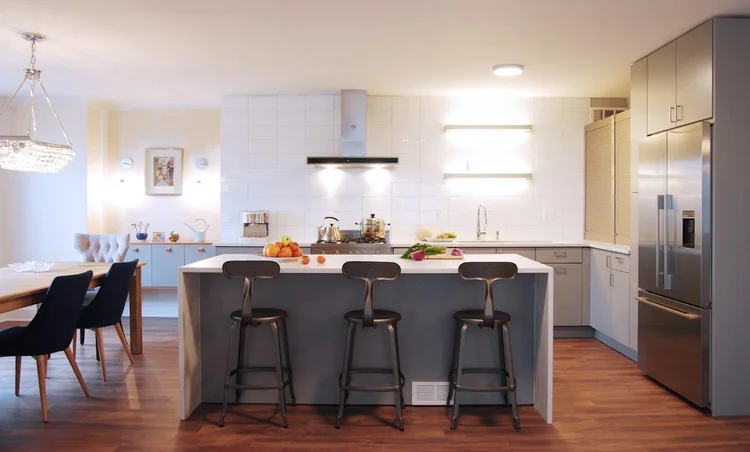Wide view of the kitchen island with bar stools, layered lighting, and streamlined cabinetry highlighting the clean lines and practical luxury of this New York home remodel.