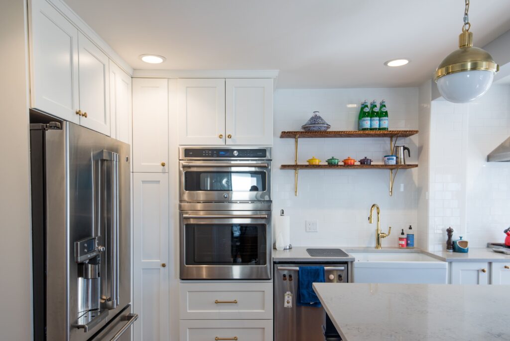 Contemporary NYC kitchen with white cabinetry, wood shelving, and brass fixtures combining timeless elegance with modern efficiency.