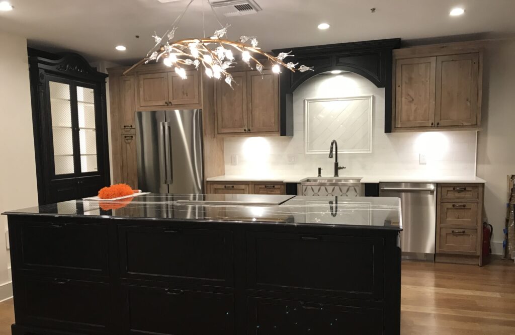 Open-concept kitchen remodel featuring a mix of natural wood cabinetry, black island base, and a statement chandelier for a sophisticated city aesthetic.