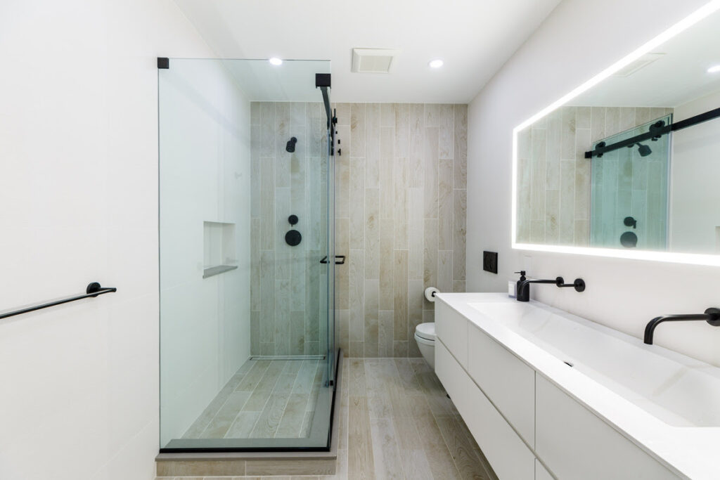 Full bathroom view with a glass-enclosed walk-in shower, floating double vanity, and backlit mirror for a sleek, spa-inspired city design.