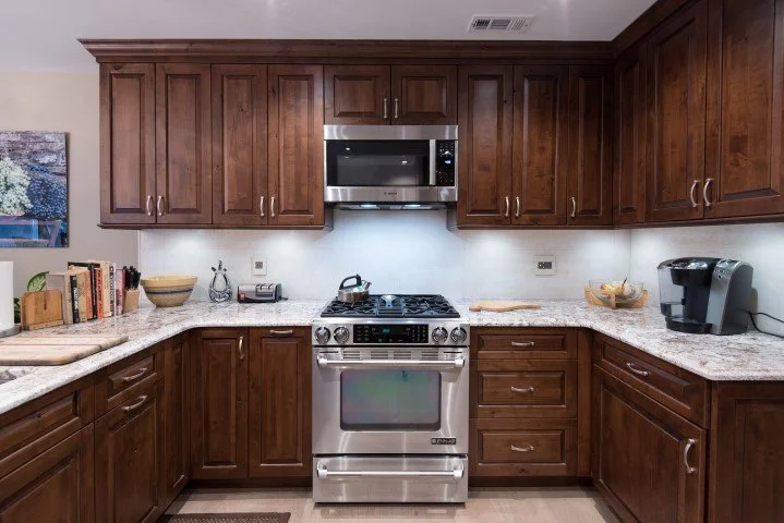 Bright kitchen remodel with natural wood cabinetry, stainless appliances, and modern pendant lighting for a refined city home.
