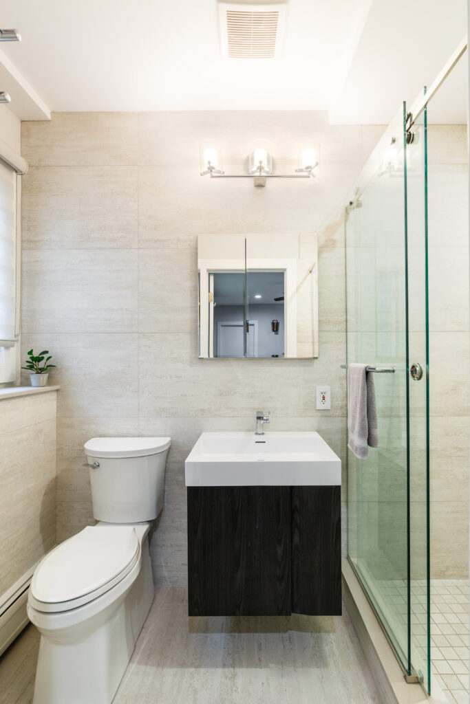Compact Manhattan bathroom remodel with a floating vanity, frameless glass shower, and contemporary lighting for a bright, modern finish.