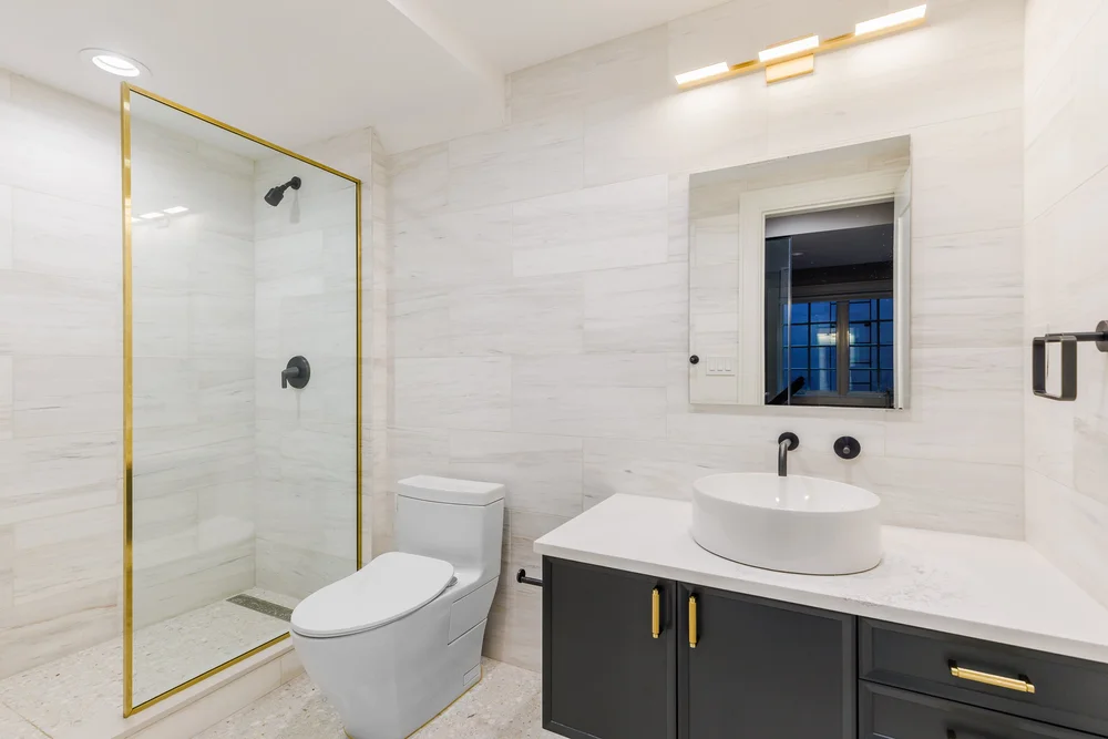 Stylish Manhattan bathroom remodel with a floating wood vanity, geometric patterned tile wall, and sleek glass shower enclosure.