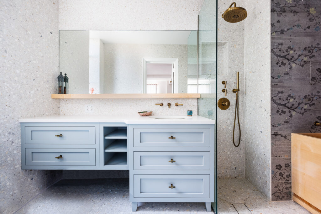 Luxury Manhattan bathroom remodel with a powder-blue double vanity, brass fixtures, and a frameless glass shower for a timeless yet modern look.
