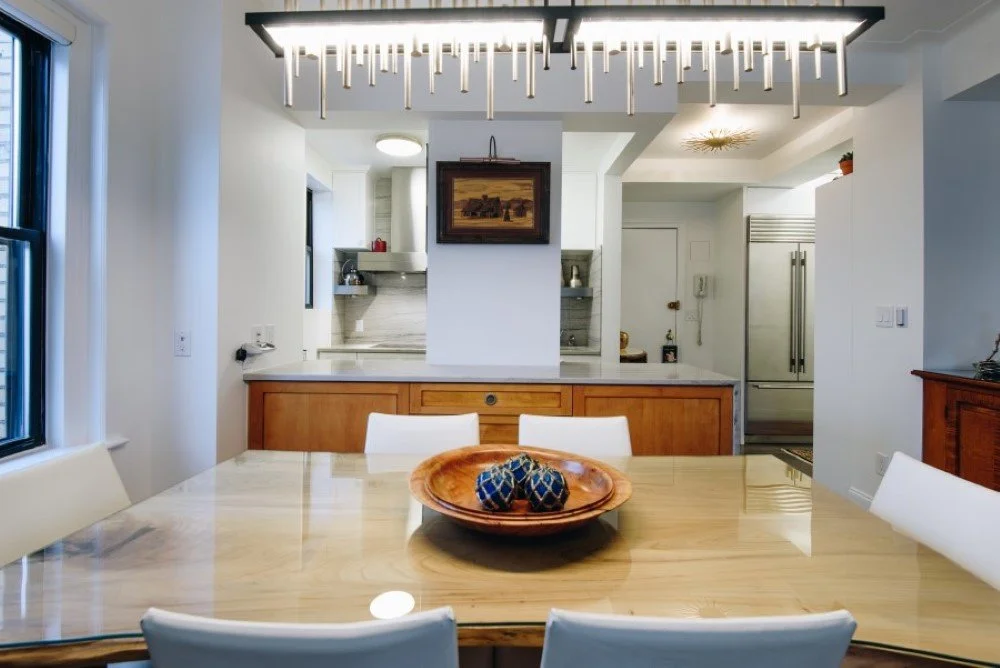 Open-plan kitchen with wood cabinetry and waterfall-edge counters, seamlessly connecting to the dining area for urban entertaining.