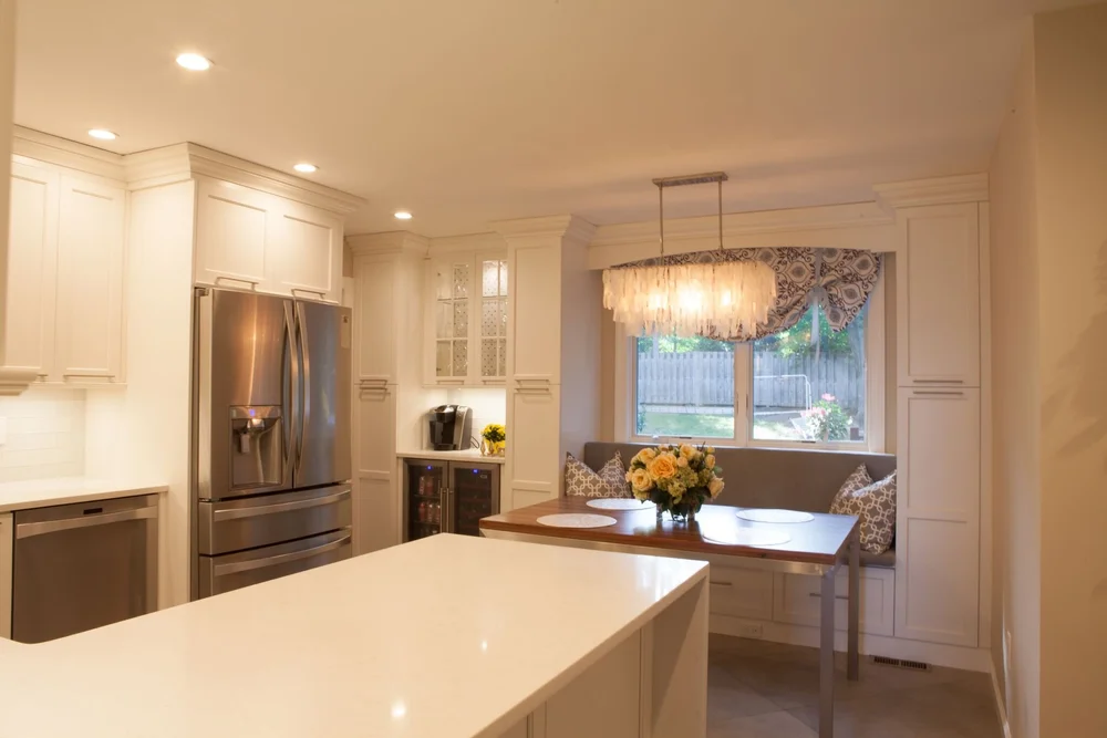 Bright breakfast nook with a wood dining table, upholstered banquette seating, and a statement chandelier perfect for blending dining and kitchen space in NYC homes.