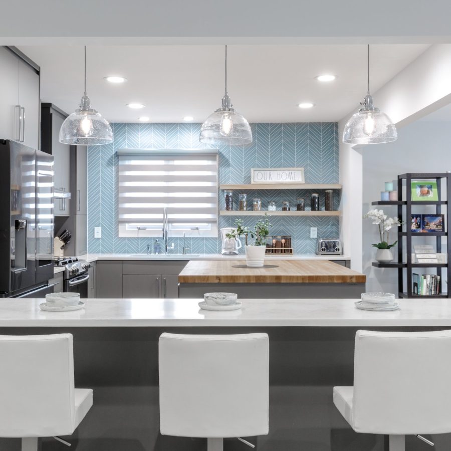 10156 Brownstone renovation in Manhattan. Modern kitchen renovation featuring pendant lighting, white bar seating, butcher block island, and a blue herringbone backsplash for a fresh, contemporary look.