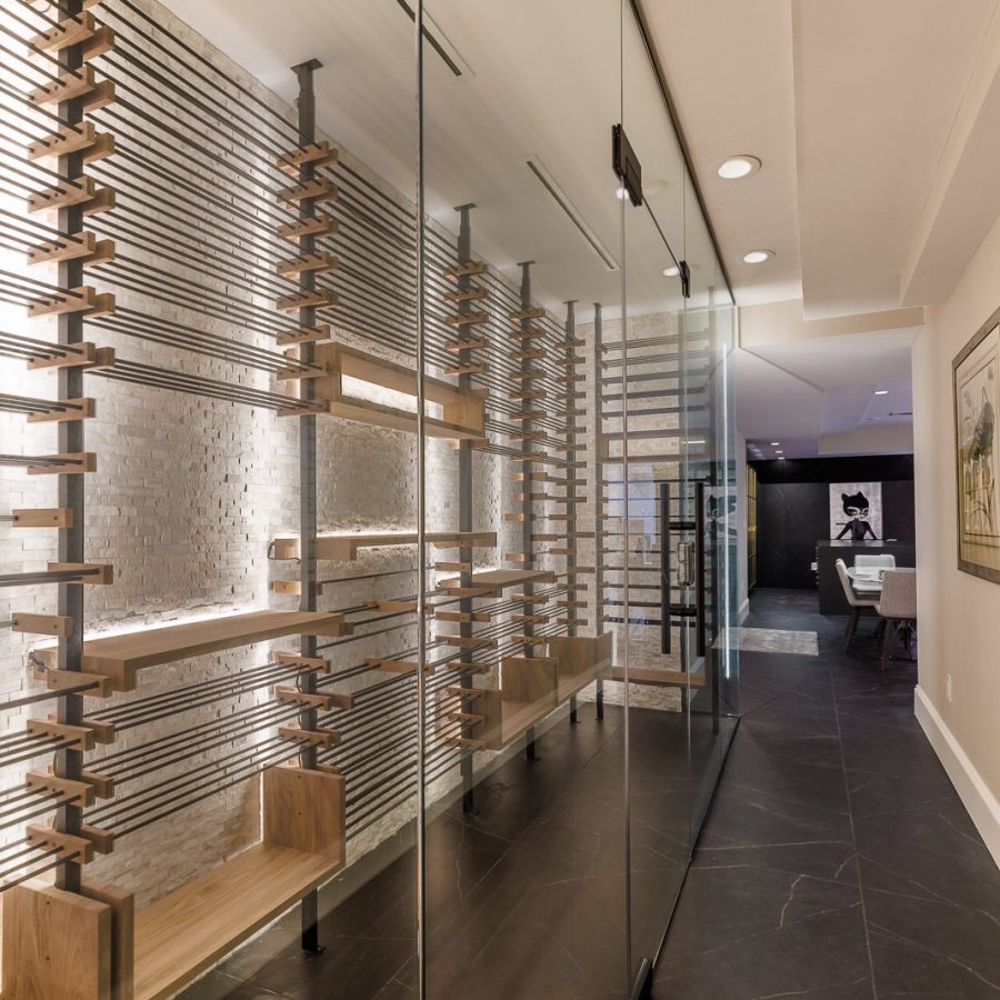 10284 Home remodeling contractor in Midtown. Modern hallway with a glass-enclosed wine storage area featuring horizontal wooden racks, dark tile flooring, recessed lighting, and a view into a contemporary dining space.