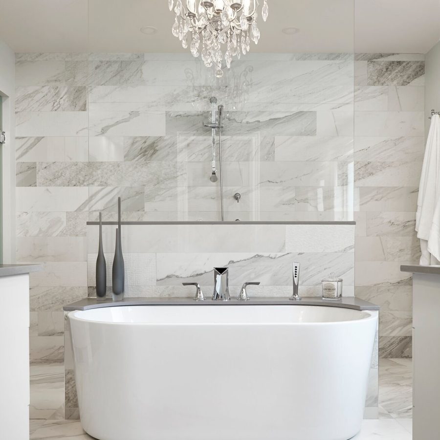 10324 Luxury bathroom featuring a freestanding soaking tub, marble tile walls and floors, a glass shower partition, and an elegant crystal chandelier overhead.